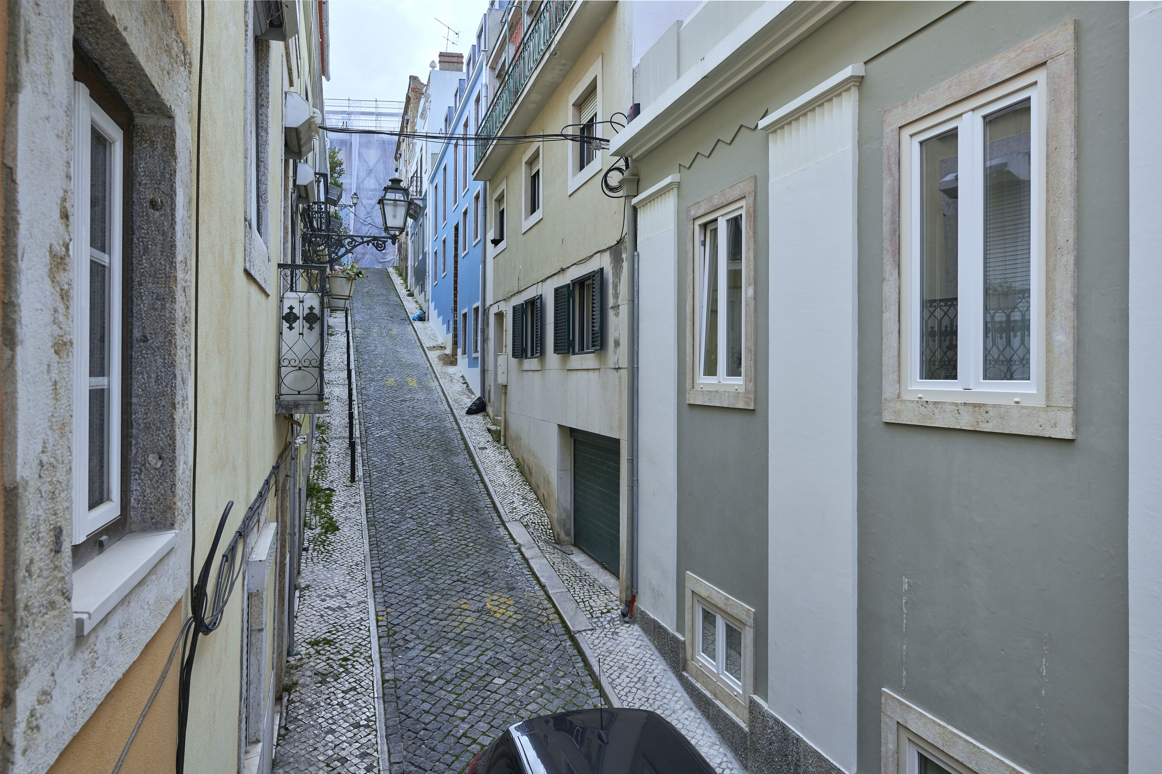 Eine schmale Kopfsteinpflasterstraße, gesäumt von Gebäuden mit Balkonen und Fenstern.