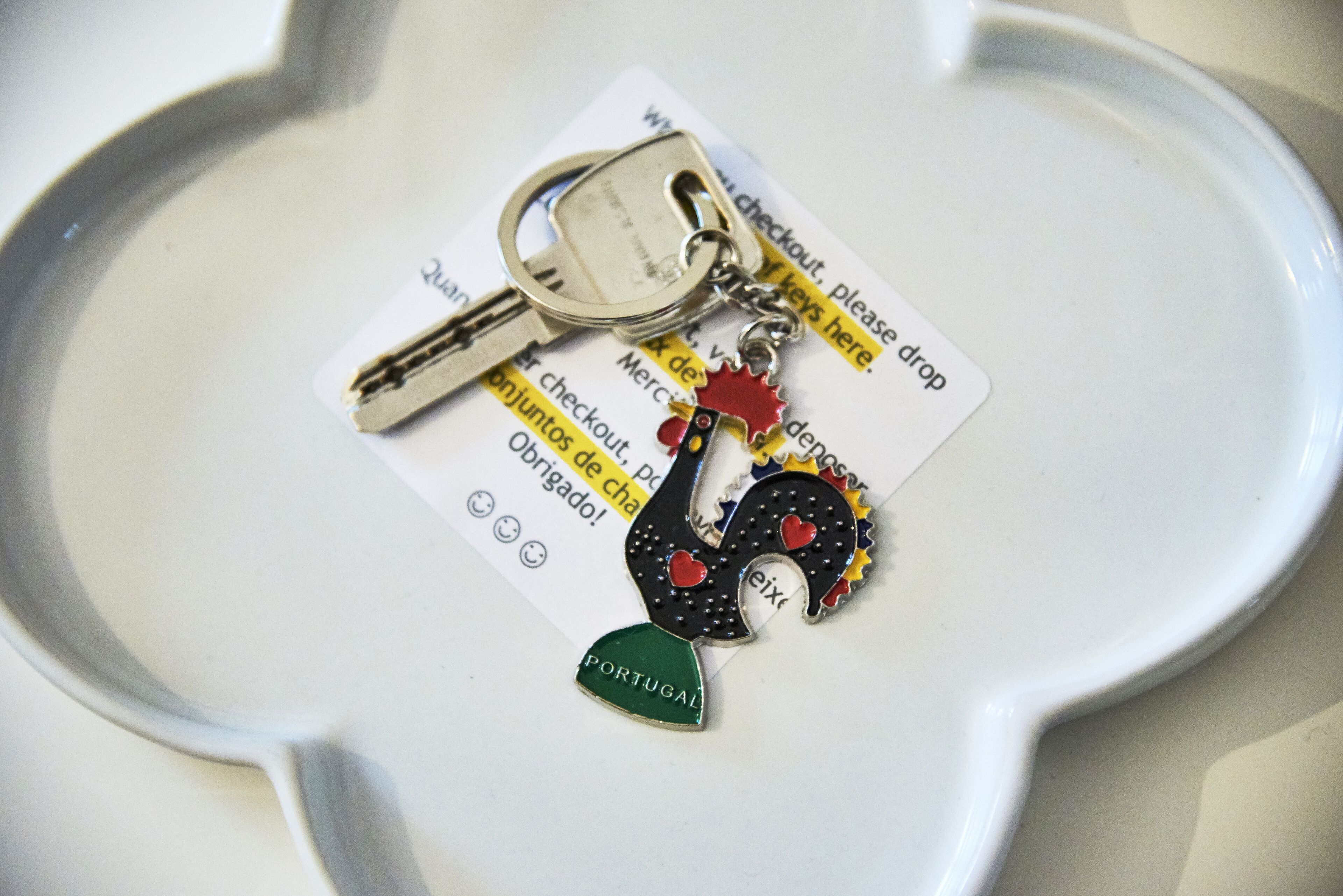 Un plato blanco con un llavero y una llave, un llavero con un dije en forma de corazón, y una llave con un sujetalaves.