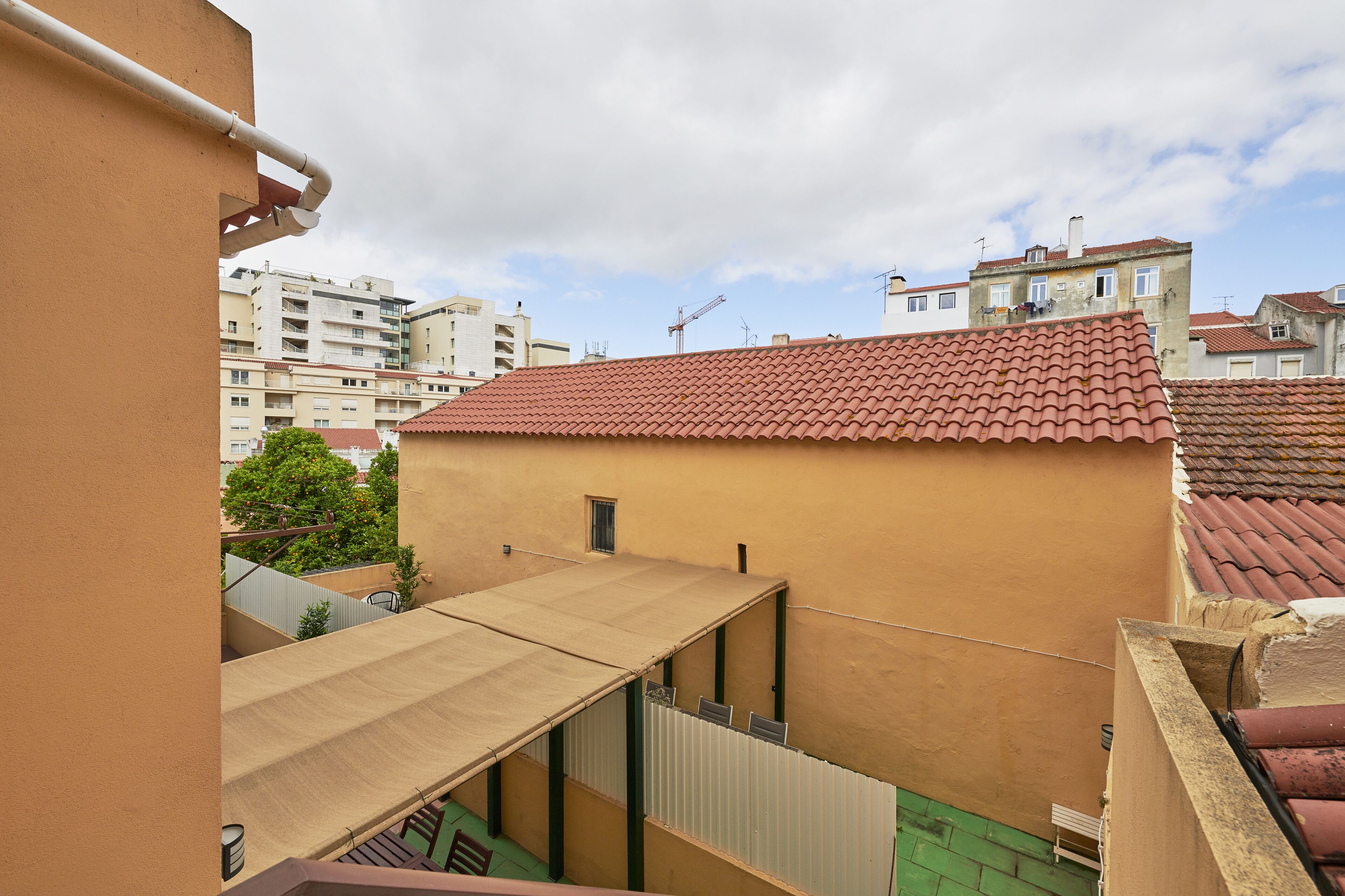 Un edificio residencial con techo de tejas rojas, un área de patio techada y vistas de edificios vecinos.