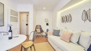 Ein modernes Wohnzimmer mit einem weißen Sofa, einem Esstisch mit Stühlen und einem gemusterten Teppich.