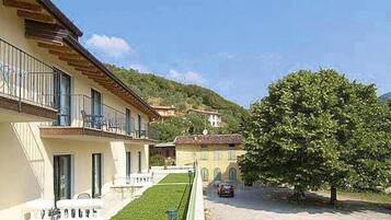 Un immeuble doté d’un balcon, d’une pelouse bien entretenue et d’un arbre devant.