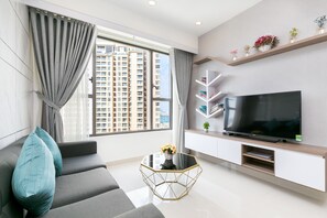 A modern living room with a sofa, a glass coffee table, a flat-screen TV, and a bookshelf. - Rivergate Residence Apartments (Ho Chi Minh City)