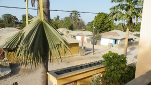 A residential area with houses, palm trees, and a clear sky. - Kounakito - Meaning 'welcome' (Oussouye)