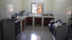 A compact kitchen with a gas stove, oven, and a refrigerator. - Kounakito - Meaning 'welcome' (Oussouye)