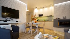 Uma sala de estar moderna com uma TV de tela plana, um sofá, uma mesa de jantar com cadeiras e uma lareira.