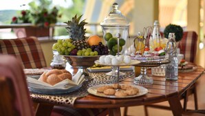 Um buffet de café da manhã com diversas frutas, doces e bebidas sobre uma mesa de madeira.