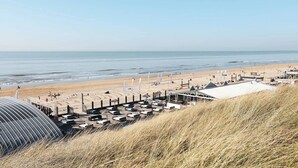 Ein Hotel am Strand mit einer langen Pier, Strandsonnenschirmen und einem großen überdachten Bereich.