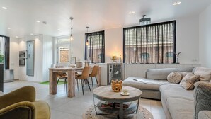 Ein modernes Wohnzimmer mit einer Couch, einem runden Couchtisch und einem Essbereich mit Stühlen und Tisch.