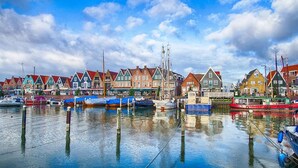 Ein Yachthafen am Wasser mit bunten Häusern und vertäuten Booten.