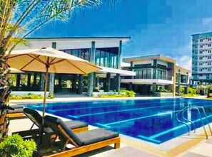 Relax by the pool surrounded by lush landscaping and palm trees, with lounge chairs and umbrellas at your disposal.