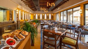 Un restaurante con zona de bufé, muebles de madera y grandes ventanales.