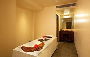 A room with a massage table, a small wooden cabinet, and a mirror. - Marquis Beach Resort (Candolim)