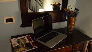 A laptop on a desk with a magazine and a vase with plants. - Fattoria Alvaneta (Padula)
