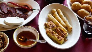 A table with various dishes including sliced meats, cheese, breadsticks, and a bowl of nuts. - Fattoria Alvaneta (Padula)
