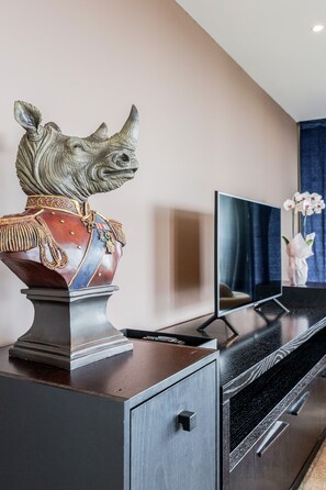 A modern living room with a television, a decorative rhinoceros bust, and a cabinet. - Point West Apartments (London)