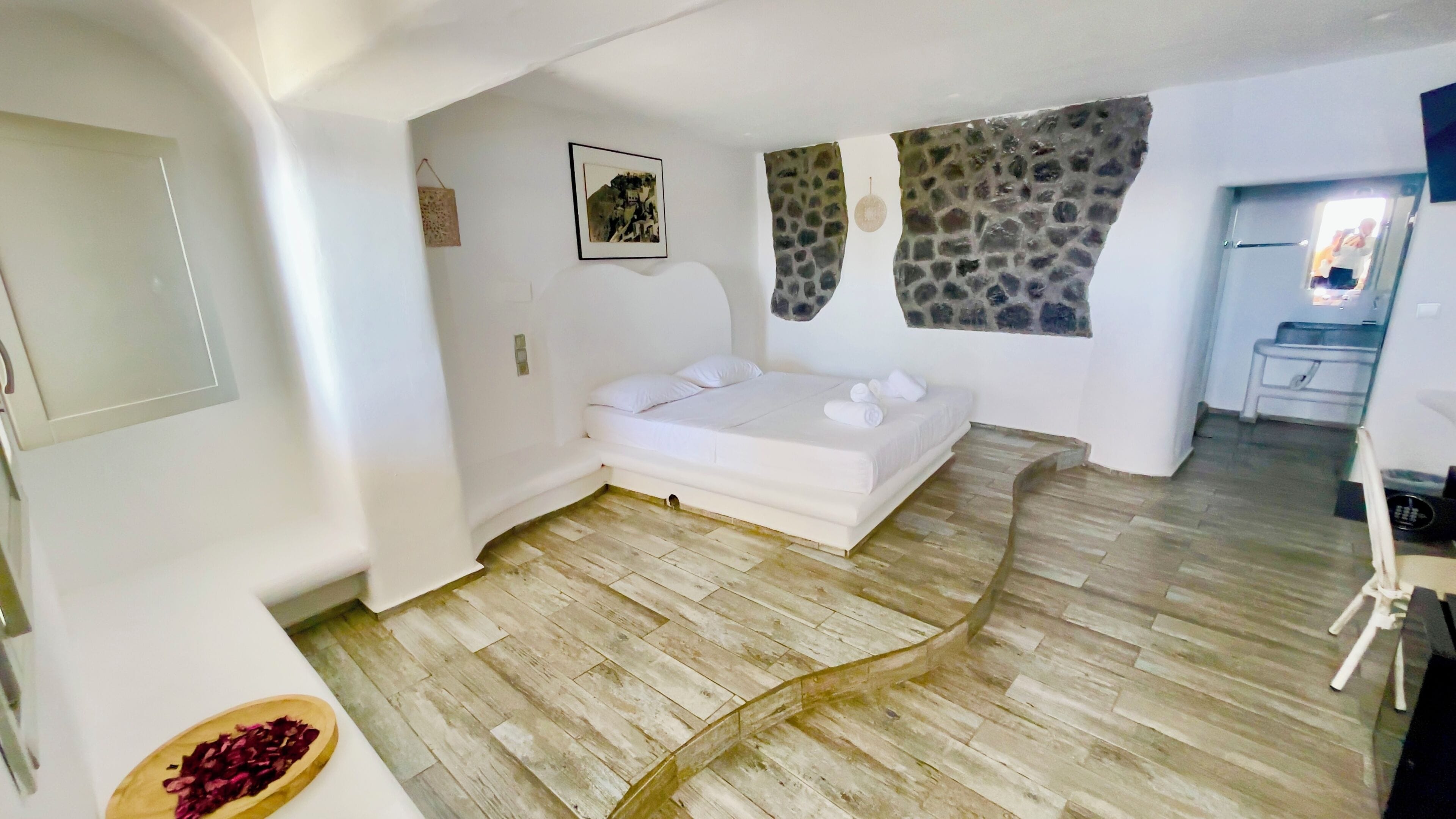 A bedroom with a bed, a stone wall, a picture, and a wooden floor.
