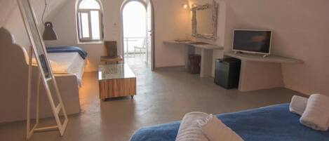 A room with a bed, a desk, a television, and a window.