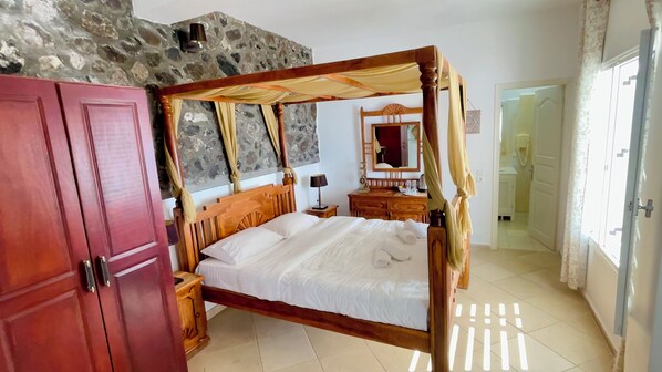 Un dormitorio con cama con dosel, armario de madera, pared de piedra y un espejo.