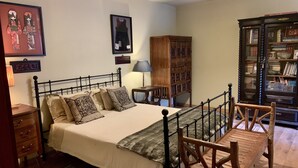 Un dormitorio con cama, muebles de madera, una estantería y una lámpara.
