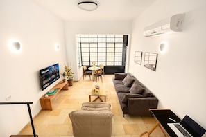 A modern living room with a sofa, coffee table, and a TV displaying a video call.
