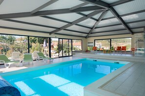 A swimming pool with lounge chairs and a covered area with large windows. - Casas de Sequeiros (Aguiar da Beira)