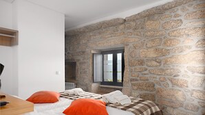 Un dormitorio con dos camas, paredes de piedra, una ventana y vistas.