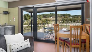 Una sala de estar moderna con un sofá, una mesa de comedor con sillas y un ventanal corredero que da a un patio exterior.