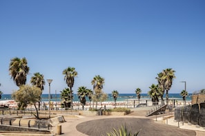 A beach promenade with palm trees, a wooden boardwalk, and a view of the beach and ocean. - Sunny Studio Near the Beach by Sea N Rent (Tel Aviv)