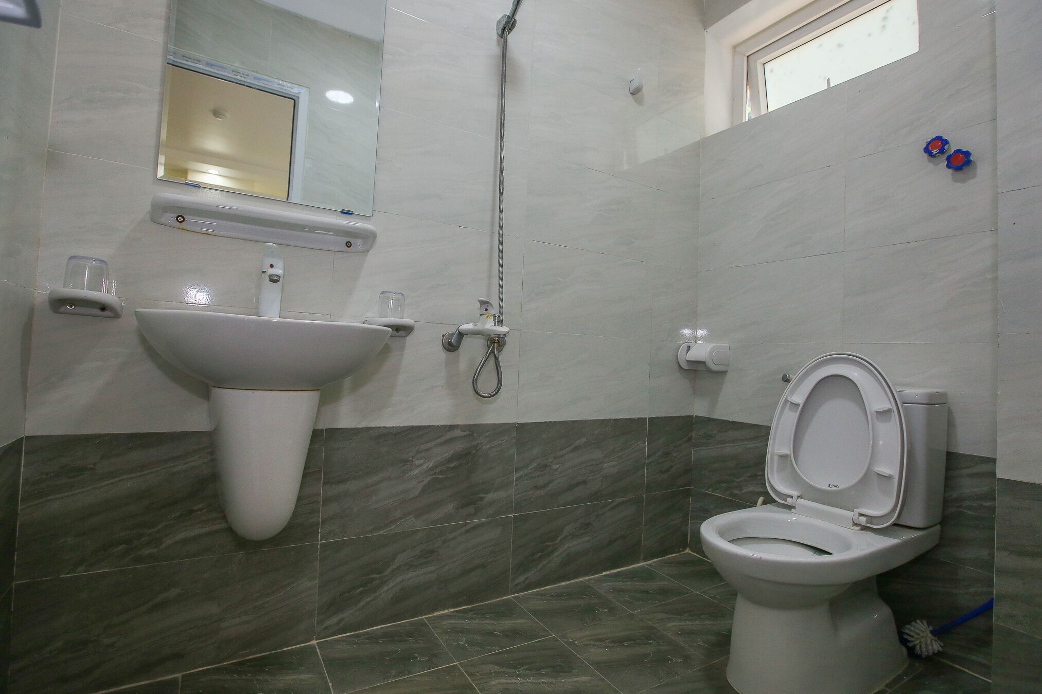 Un baño con lavamanos blanco, inodoro y ducha.