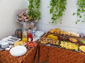 A buffet table with various food items, including fruits, bread, and pastries. - Cat Ba Green Hotel (Hai Phong)