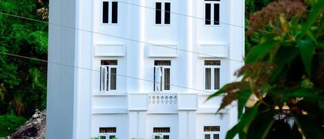 A white multi-story building with a traditional architectural style, featuring multiple windows and a flat roof.