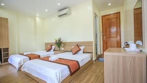 A hotel room with three beds, a wooden reception desk, and a wall-mounted air conditioner. - Cat Ba Green Hotel (Hai Phong)