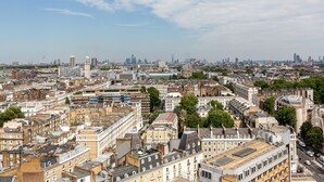Un paysage urbain avec des bâtiments denses, une tour imposante et un ciel dégagé.