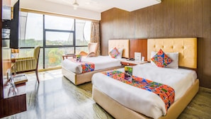 Habitació d'hotel amb dos llits, televisió i una finestra gran amb vistes a la ciutat.