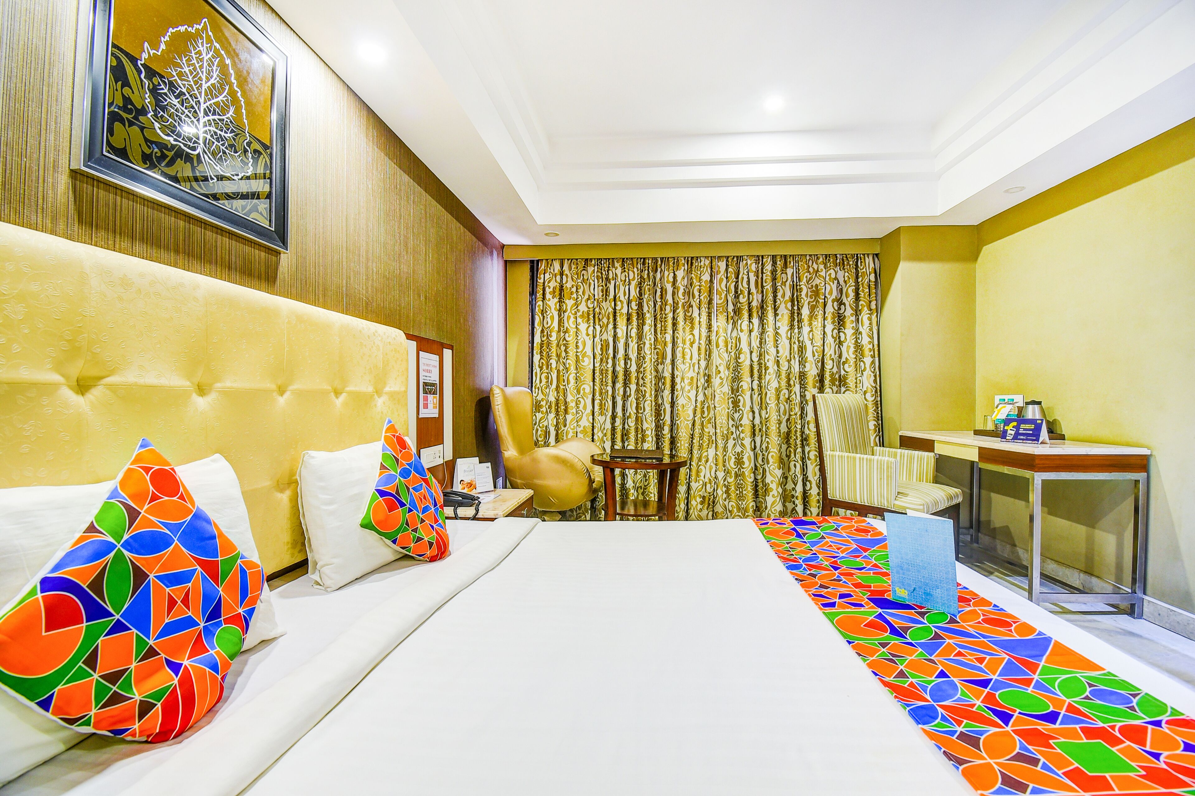A hotel room with a bed, a desk, a chair, and a curtain.
