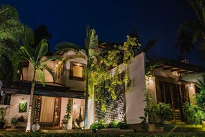 Una casa moderna con una entrada luminosa, una pared de piedra con plantas y un ventanal grande.