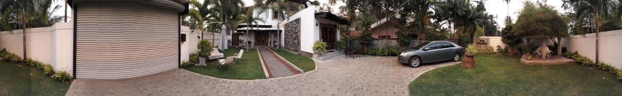 A gated residential area with a paved driveway leading to a house, a parked car, and a well-maintained lawn.