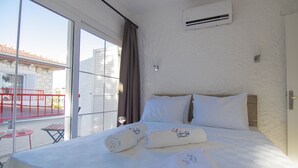Hotellihuone, jossa on suuri sänky, ikkuna, josta on näkymä rakennukseen, ja parveke, jossa on punainen kaide.