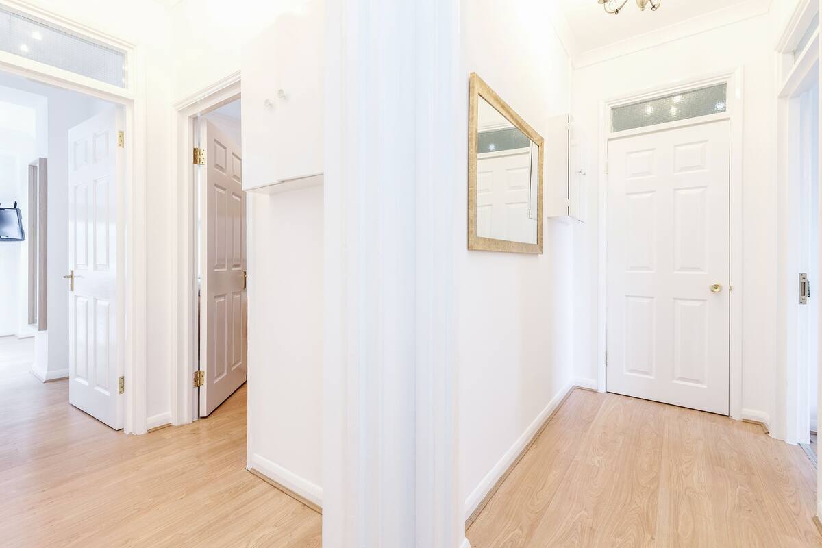 A hallway with white doors, a mirror, and a light fixture.