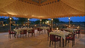 An outdoor dining area with tables and chairs, under a large tent with a patterned canopy. - Jawai Leopard Safari Lodge (Sumerpur)