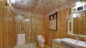 A wooden-paneled bathroom with a glass shower enclosure, a toilet, and a sink with a mirror. - Jawai Leopard Safari Lodge (Sumerpur)
