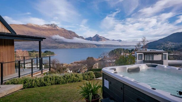 A hot tub with a view of mountains and a lake.