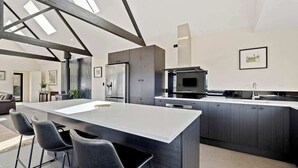 A modern kitchen with a central island, dark cabinetry, and a large window above the island.
