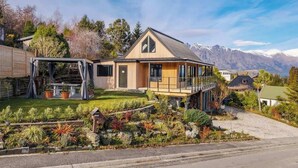 A modern house with a large deck, a covered patio, and a well-maintained garden.
