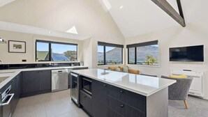 A modern kitchen with a large island, dark cabinetry, and large windows offering mountain views.