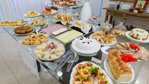 Una mesa de buffet con diferentes opciones de comida, incluyendo pasteles, sándwiches y postres.