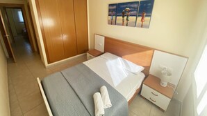 A hotel room with a bed, a wooden wardrobe, a nightstand, a coffee maker, and a painting of a beach scene. - Sueños De Denia, 2 bedrooms, by Bookindenia (Denia)