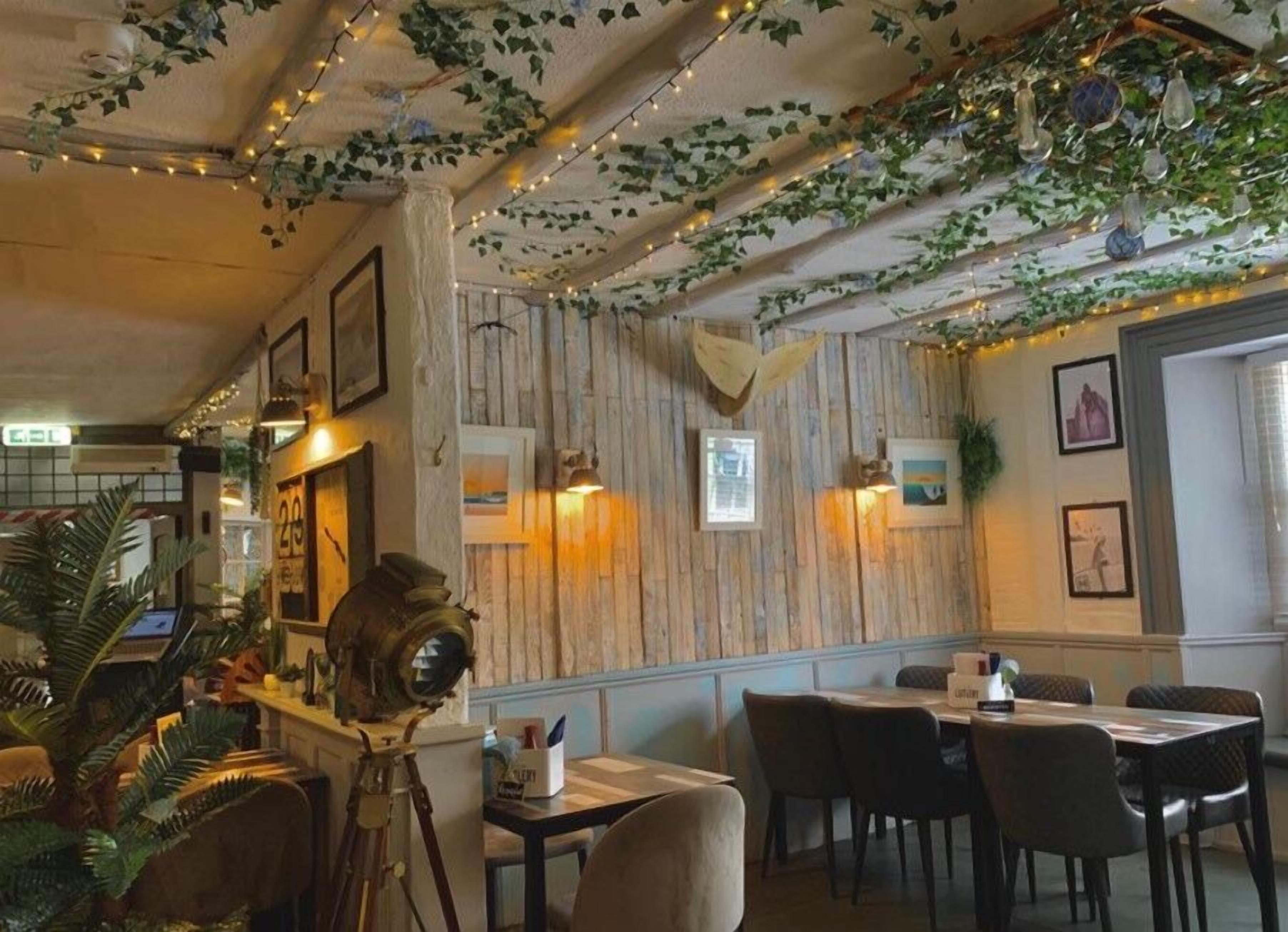 Interior de restaurante con paredes de paneles de madera, luces colgantes y cuadros enmarcados.