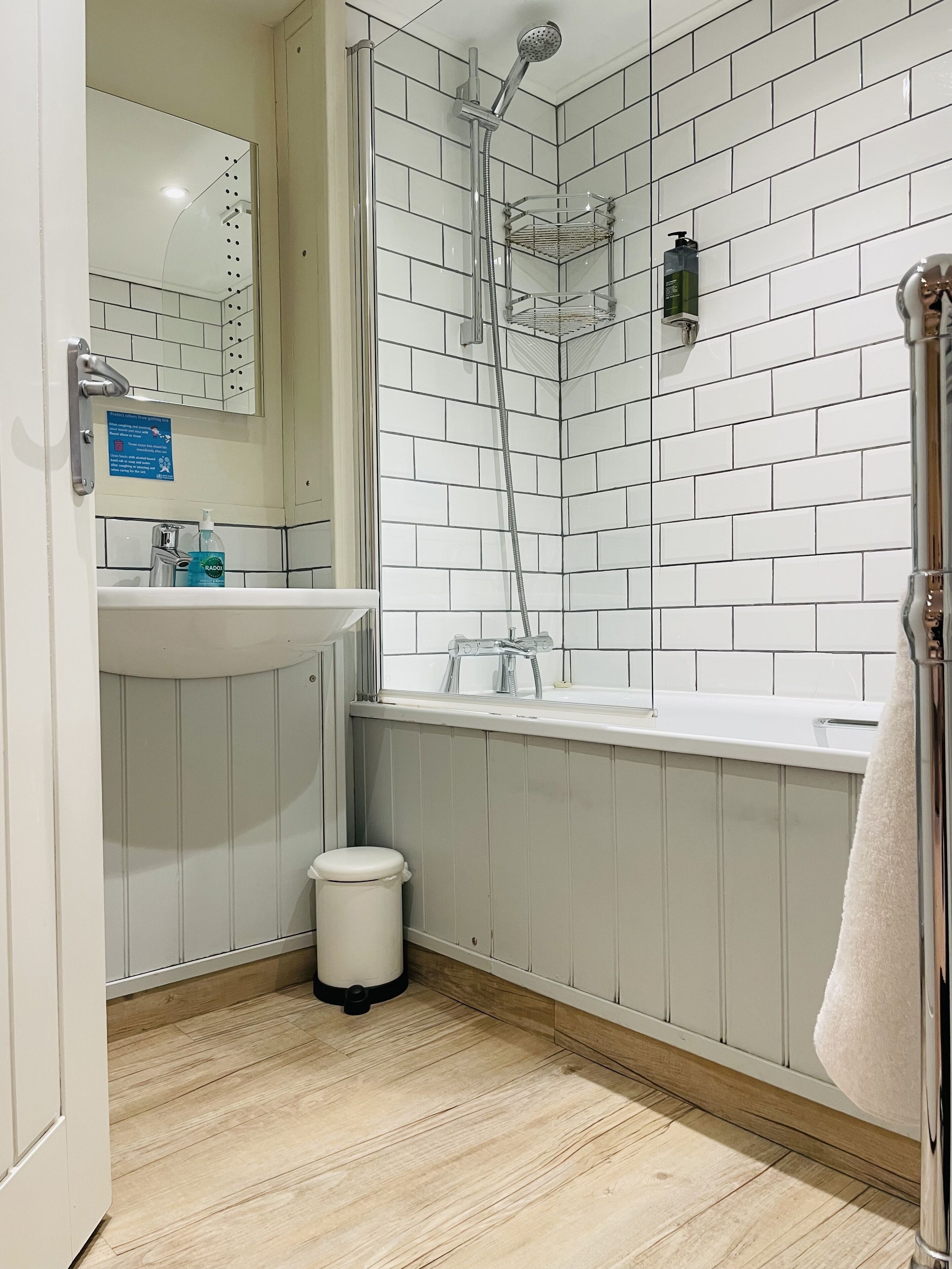 Ein modernes Badezimmer mit einer weißen Duschkabine, einem Waschbecken mit Spiegel und einer Toilette.