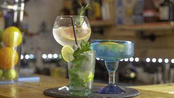 Tres cócteles sobre una barra, con un fondo desenfocado de botellas y vasos.